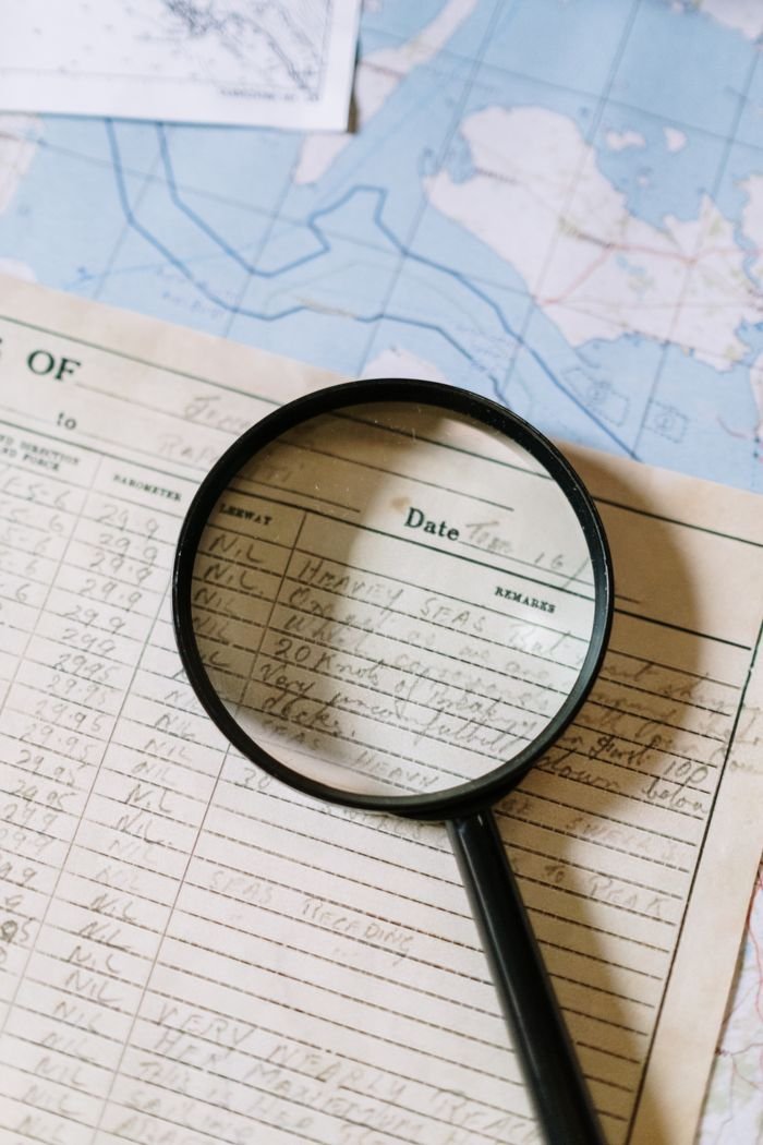 Home Close-up of a magnifying glass over a handwritten document on a map.
